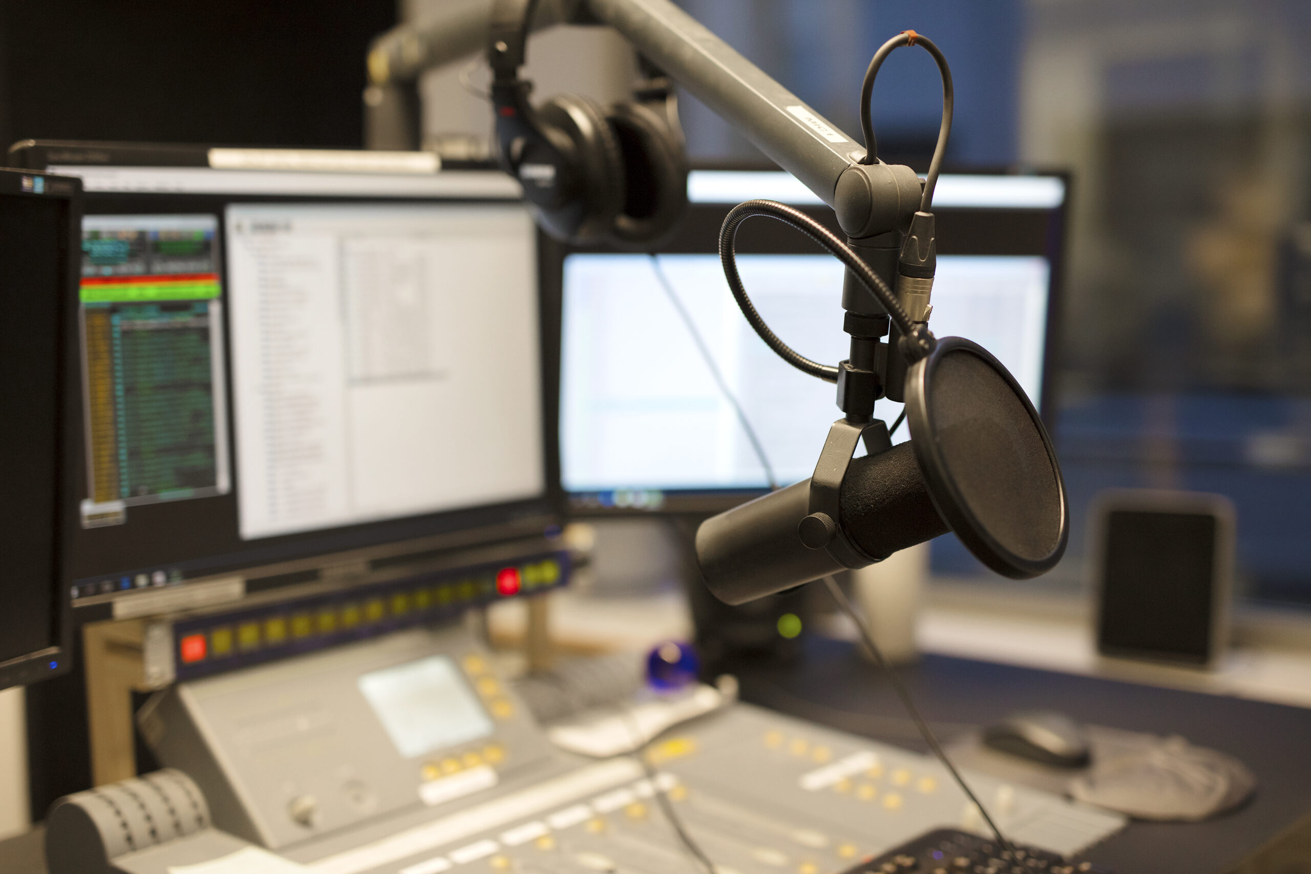 Microphone in front of the sound mixer and computers in broadcasting radio studio. New radio station studio.
