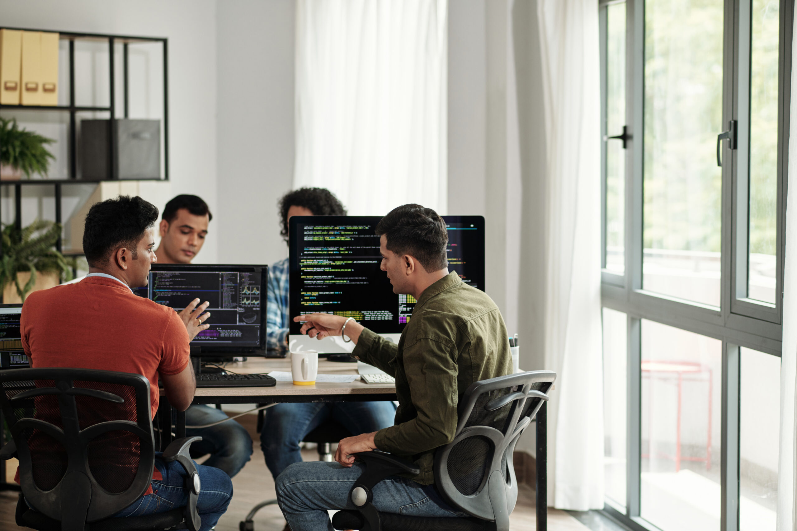 Software developers discussing programming code and planning how to create innovative software while sitting around their computer screens