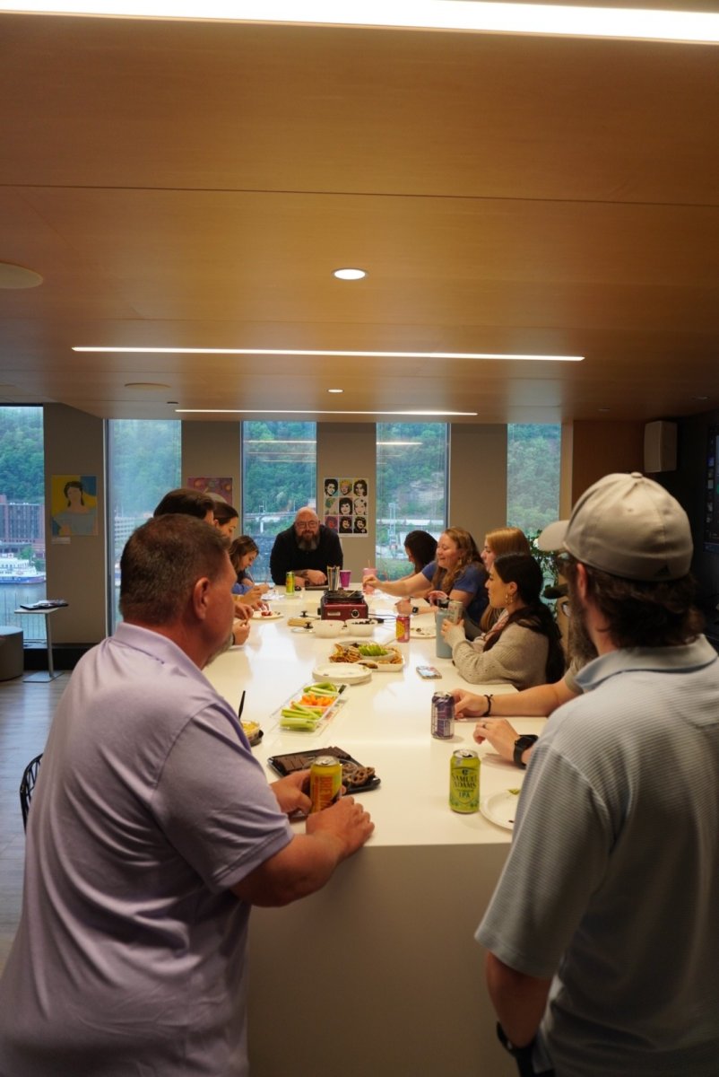 Team members gathered around a table with snacks and drinks in a conference room