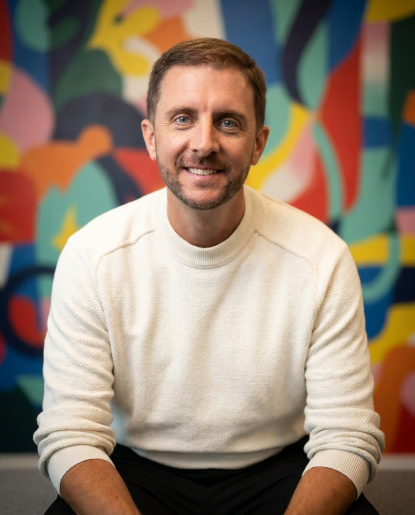 close up of Brad Cook sitting in front of colorful background