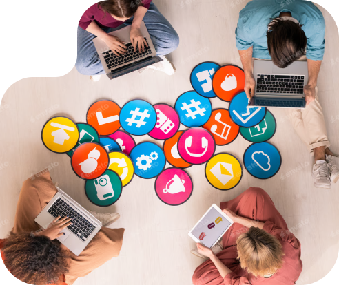 Four people sitting in a circle, on the floor, working on laptops with icon circular cards in between them