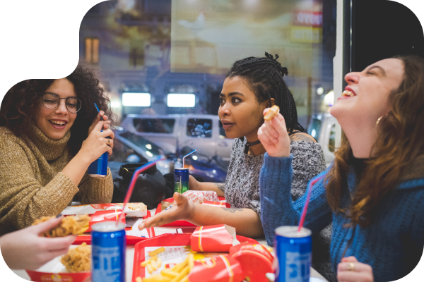 3 Women talking and laughing around a table full of food in a restaurant setting