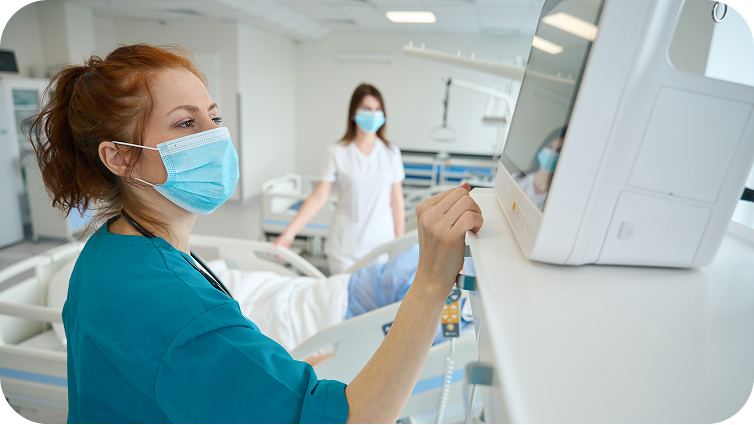A doctor and a nurse in face masks examining a patient on a monitor.