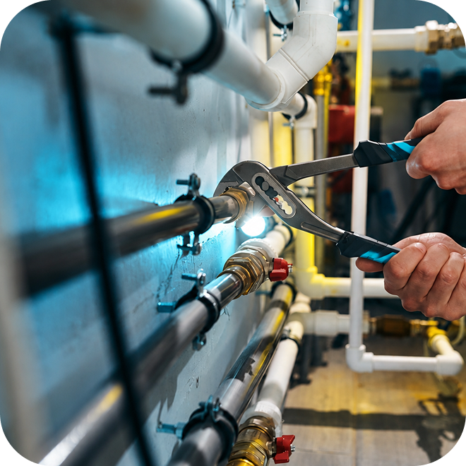 A person working on a plumbing shut off valve with a pair of channel locks.