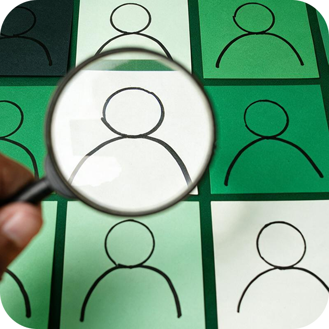 A person using a magnifying glass looking a a grid of people silhouettes.