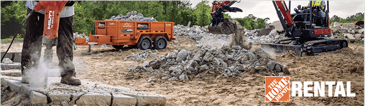 A person jack hammering concrete and an excavator scooping up the concrete and putting it into a trailer